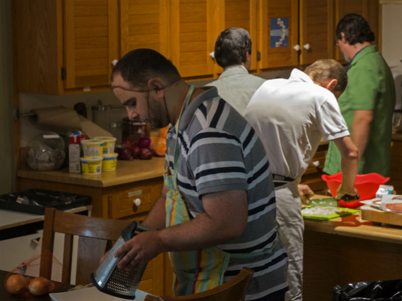 Des participants cuisinent ensemble dans la cuisine commune du 1704 St-Georges
